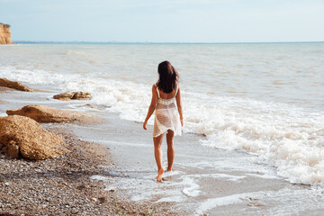 Fototapeta na wymiar woman walking along the seashore on the beach walking travel vacation