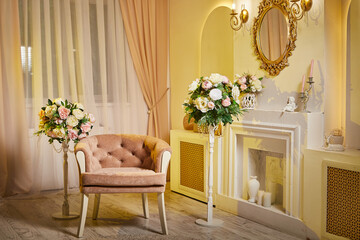 Interior of stylish living room with fireplace. A beautiful room with an armchair, a fireplace, a mirror and bouquets of flowers. A photo studio, a place for photo shoots, a location for shooting