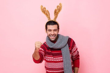Christmas studio shot portrait of cheerful Caucasian man wearing sweater and fancy reindeer...