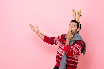 Christmas studio shot portrait of surprised Caucasian man wearing sweater and fancy reindeer...