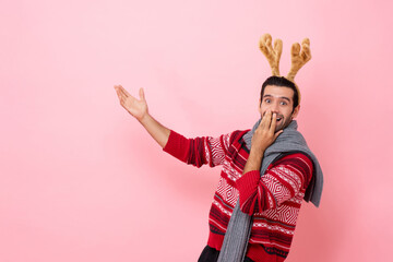 Christmas studio shot portrait of shocked Caucasian man wearing sweater and fancy reindeer headband...
