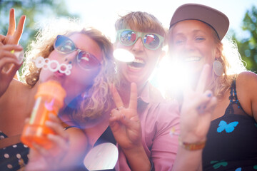 Portrait, peace sign and happy friends in sunglasses outdoor, blowing bubbles and funny laugh...