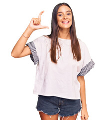 Young hispanic woman wearing casual clothes smiling and confident gesturing with hand doing small size sign with fingers looking and the camera. measure concept.