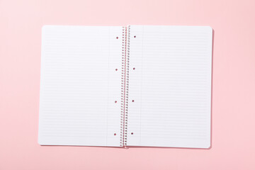 Open notepad on pink background, top view