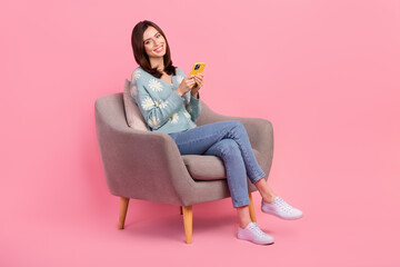 Full length photo of attractive young woman using her new apple smartphone sit comfortable chair...