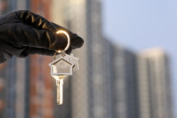 Apartment purchase in winter, woman in gloves holding house keys on background of new buildings....