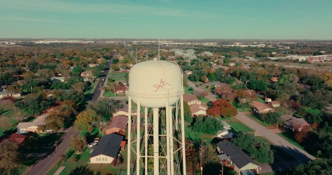 Georgetown, Texas water tower and neighborhood on blue sky sunny fall day, aerial drone tilt down in Austin, Texas suburb