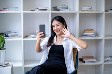 Fototapeta na wymiar Young Asian woman takes a selfie with a smartphone camera or records a vlog video. Makes a long-distance video call.