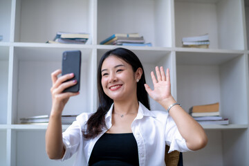 Young Asian woman takes a selfie with a smartphone camera or records a vlog video. Makes a long-distance video call.