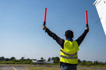 Back view aircraft controller using gesture sticks control small plane in airfield © Jack Tamrong