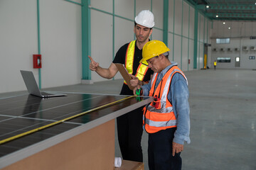 Worker and engineer discussing over solar panel in warehouse. This is a freight transportation and distribution warehouse.