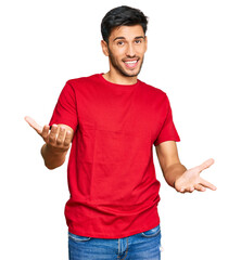 Young handsome man wearing casual red tshirt smiling cheerful with open arms as friendly welcome, positive and confident greetings