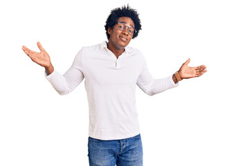 Handsome african american man with afro hair wearing casual clothes and glasses clueless and...