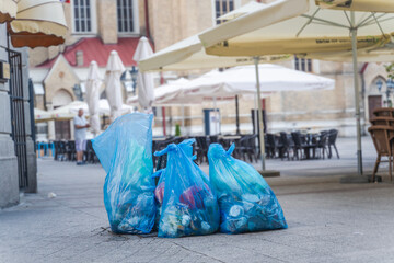 Blue garbage bags on the pavement on the street of a European city, garbage service concept