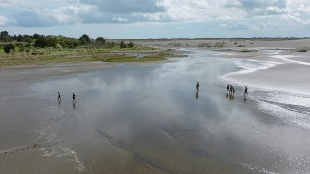 Aerial: People walking on the beach in the town of Port Waikato. New Zealand. 11 September 2023