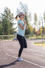 A young beautiful woman in sportswear plays sports at a local stadium. Exercise, jog and exercise at the beginning of the day. Healthy and active lifestyle.
