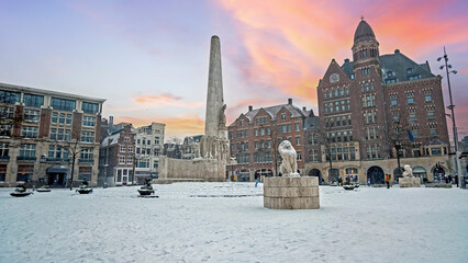 Snowy city Amsterdam at the Dam square in the Netherlands in winter - obrazy, fototapety, plakaty