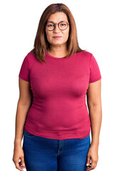 Middle age latin woman wearing casual clothes and glasses with serious expression on face. simple...