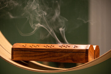 Smoke from Indian incense sticks, burning herbs smoldering inside natural wooden box with holes....