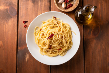 Piatto di tipici spaghetti conditi con aglio, olio e peperoncino, cibo italiano  - obrazy, fototapety, plakaty