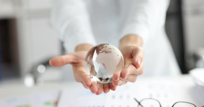 Woman holding glass globe over documents with graphs 4k movie slow motion. International relations in business concept