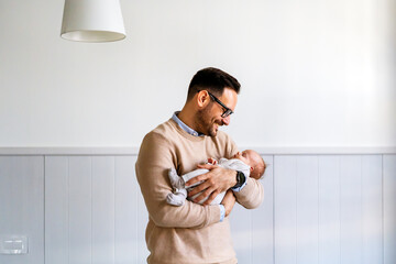 Portrait of a father hugging and kissing newborn baby. Authentic lifestyle touching tender moment. - Powered by Adobe