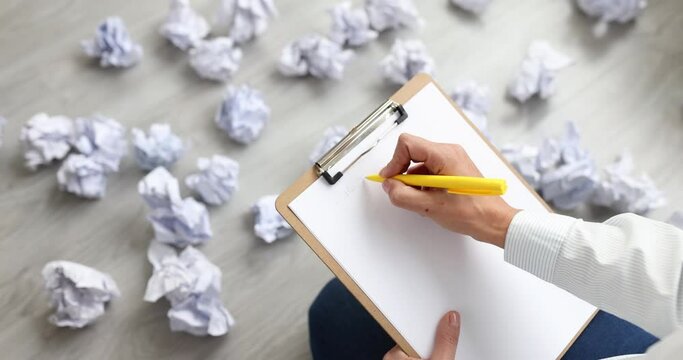 Woman writing business plan on paper among crumpled documents scattered on floor closeup 4k movie slow motion. Planning difficulties in business concept