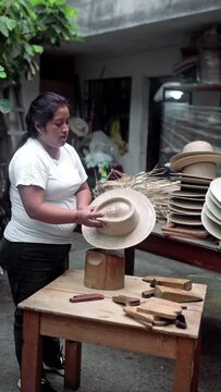 An adult Hispanic woman is trying on a natural fiber hat while crafting. Concept of handmade traditional clothing