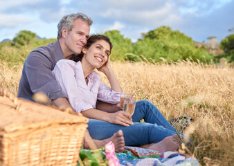 Senior couple, relax and picnic in park, grass and basket in nature for a date in retirement with love or care. Mature, woman and man in field in summer, holiday or vacation with freedom and drinks