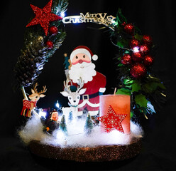 Christmas wreath in the form of a star Blue lights. Symbolic Christmas balls and ornaments. Green, white. On a black background