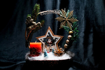 Christmas wreath in the form of a star Blue lights. Symbolic Christmas balls and ornaments. Green, white. On a black background