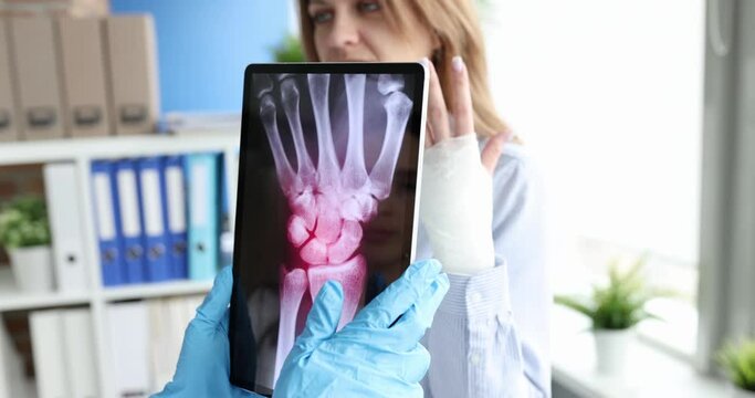 Doctor holds tablet with X-ray of the hand of patient with pain in wrist joint. Wrist injuries sprains and ruptures of ligaments of hands concept