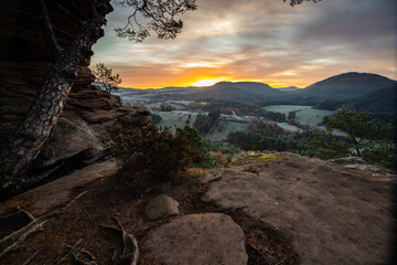 Hilly landscape shot on a sandstone rock in the forest. Cold morning mood at sunrise at a viewpoint. Winter morning in Palatinate Forest, Germany