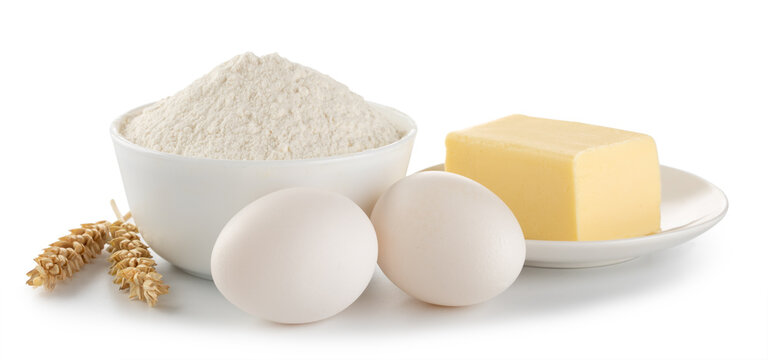 Flour in a bowl, spikelets, eggs and butter isolated on white background