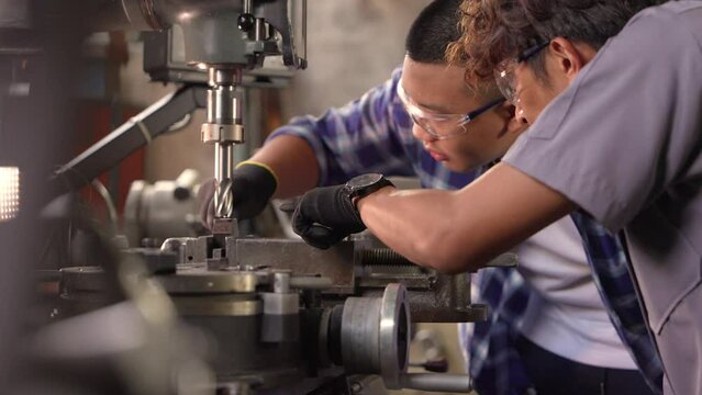Men are inspecting steel parts for machine installation. team of teacher and student are learning to use heavy machines in steel factory. workers cooperate while doing quality control of manufactured.
