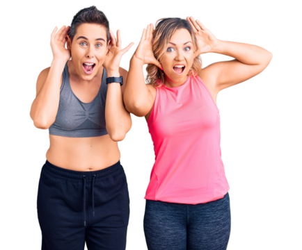 Couple of women wearing sportswear smiling cheerful playing peek a boo with hands showing face. surprised and exited