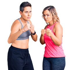 Couple of women wearing sportswear ready to fight with fist defense gesture, angry and upset face, afraid of problem