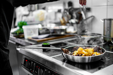 Chef cook hand cooking potato and meat food in pan at the restaurant kitchen