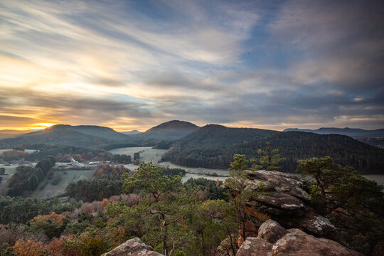 Hilly landscape shot on a sandstone rock in the forest. Cold morning mood at sunrise at a viewpoint. Winter morning in Palatinate Forest, Germany