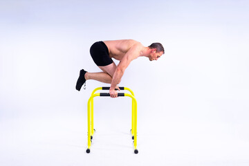 Male gymnast performing handstand on parallel bars, studio shot