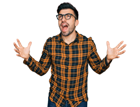 Hispanic man with beard wearing casual clothes and glasses crazy and mad shouting and yelling with aggressive expression and arms raised. frustration concept.