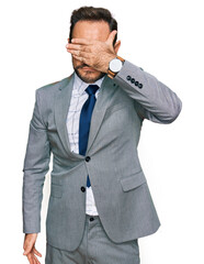 Middle age man wearing business clothes covering eyes with hand, looking serious and sad. sightless, hiding and rejection concept