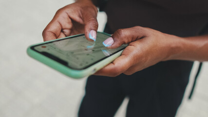 Close-up of young woman's hands browsing, zooming in on map app on her smartphone, for online tracking, internet and search