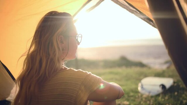 Camping, morning and back of woman in tent for summer adventure, holiday and vacation outdoors. Travel, thinking and person on campsite to explore nature for relaxing, wellness and freedom at sunrise