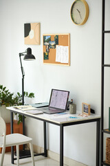 Workplace of fashion designer with laptop sketches and pinboard on wall