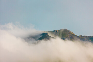 Mountains in the clouds. View of the mountain peak in the fog. Beautiful landscape with high cliffs. Dedegol. Turkey.