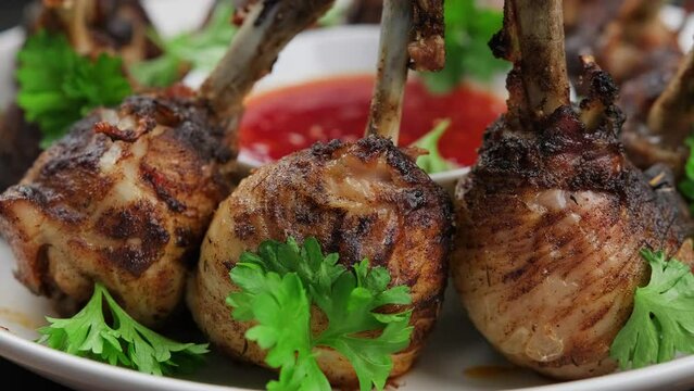 Roasted Chicken drumsticks lollipops in white plate with sweet chilli sauce. Rotating video