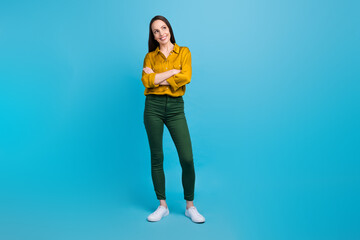 Fototapeta na wymiar Full length photo of cheerful thoughtful woman dressed yellow shirt arms folded looking empty space isolated blue color background
