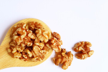 Heap of Dried Walnut Kernels on a Wooden Ladle with Some Scattered on White Background