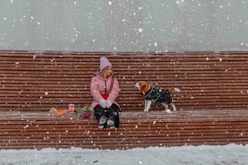 Girl with beagle dog outdoors in winter in snowfall